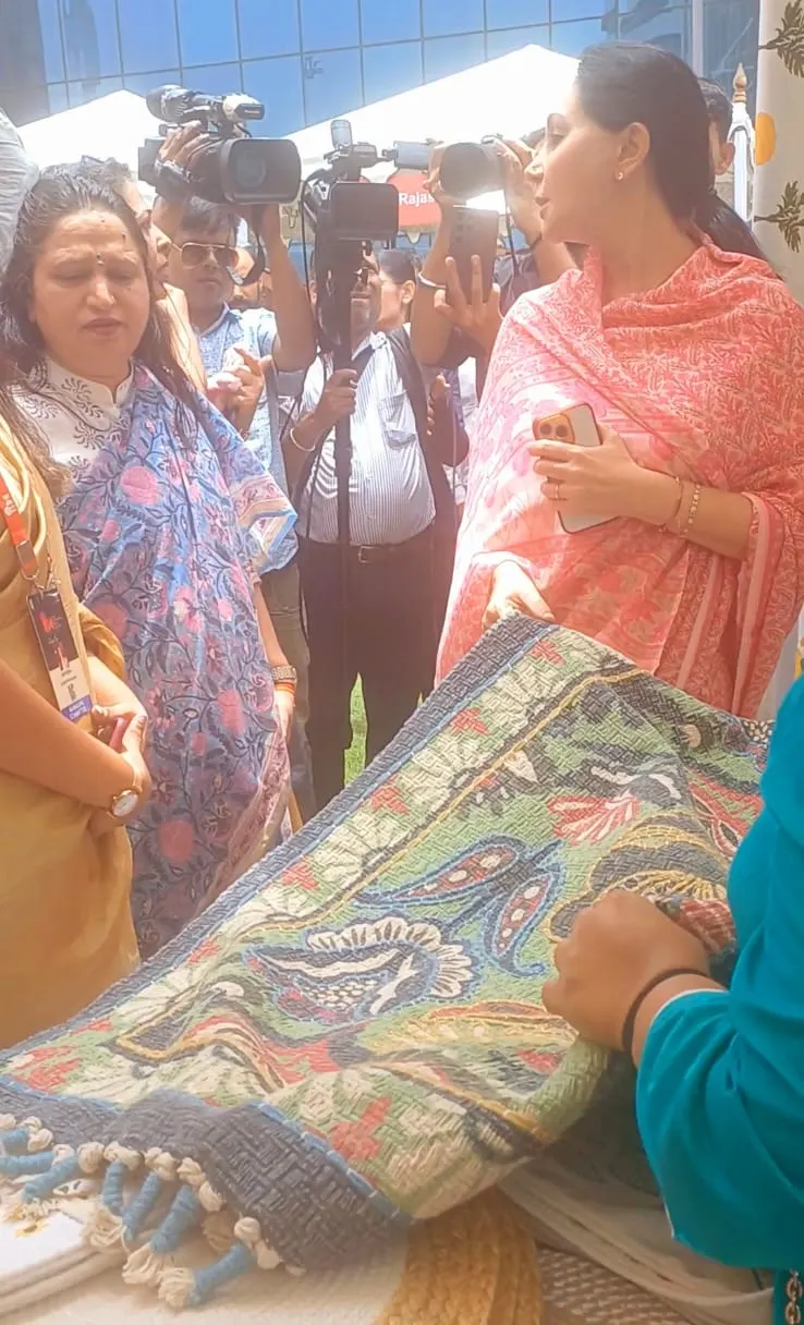 Guests looking at a patterned rug at the Dakchi stall while photographers gather behind