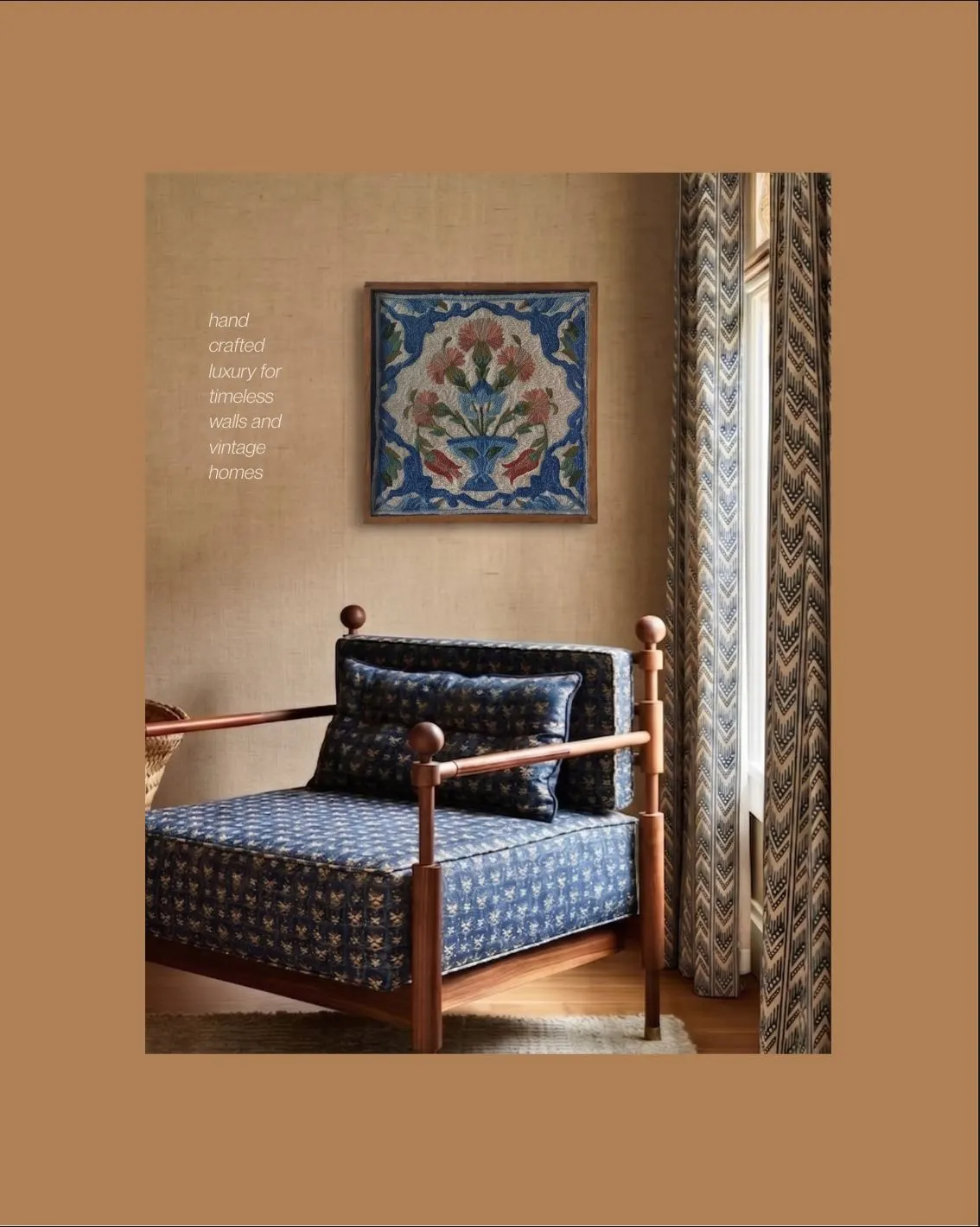 A framed embroidered floral tile in blue, coral and cream above a daybed