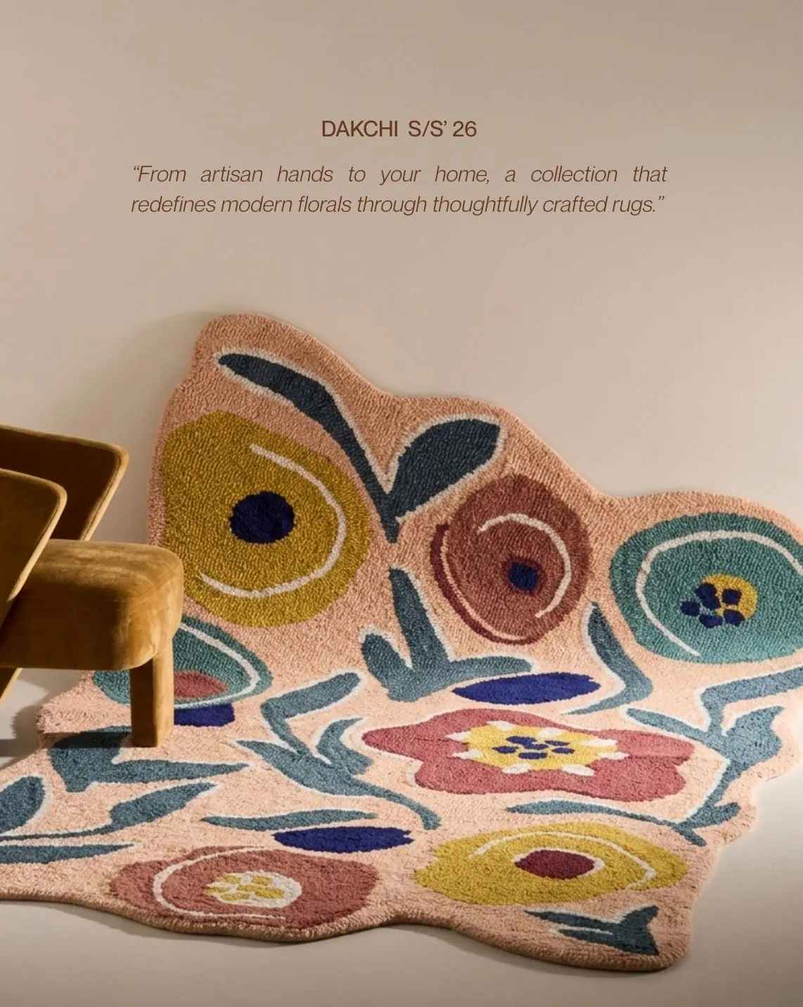 A shaped rug with large flowers in pink, teal, mustard and red beside a mustard chair. Text reads Dakchi S/S 26, from artisan hands to your home.