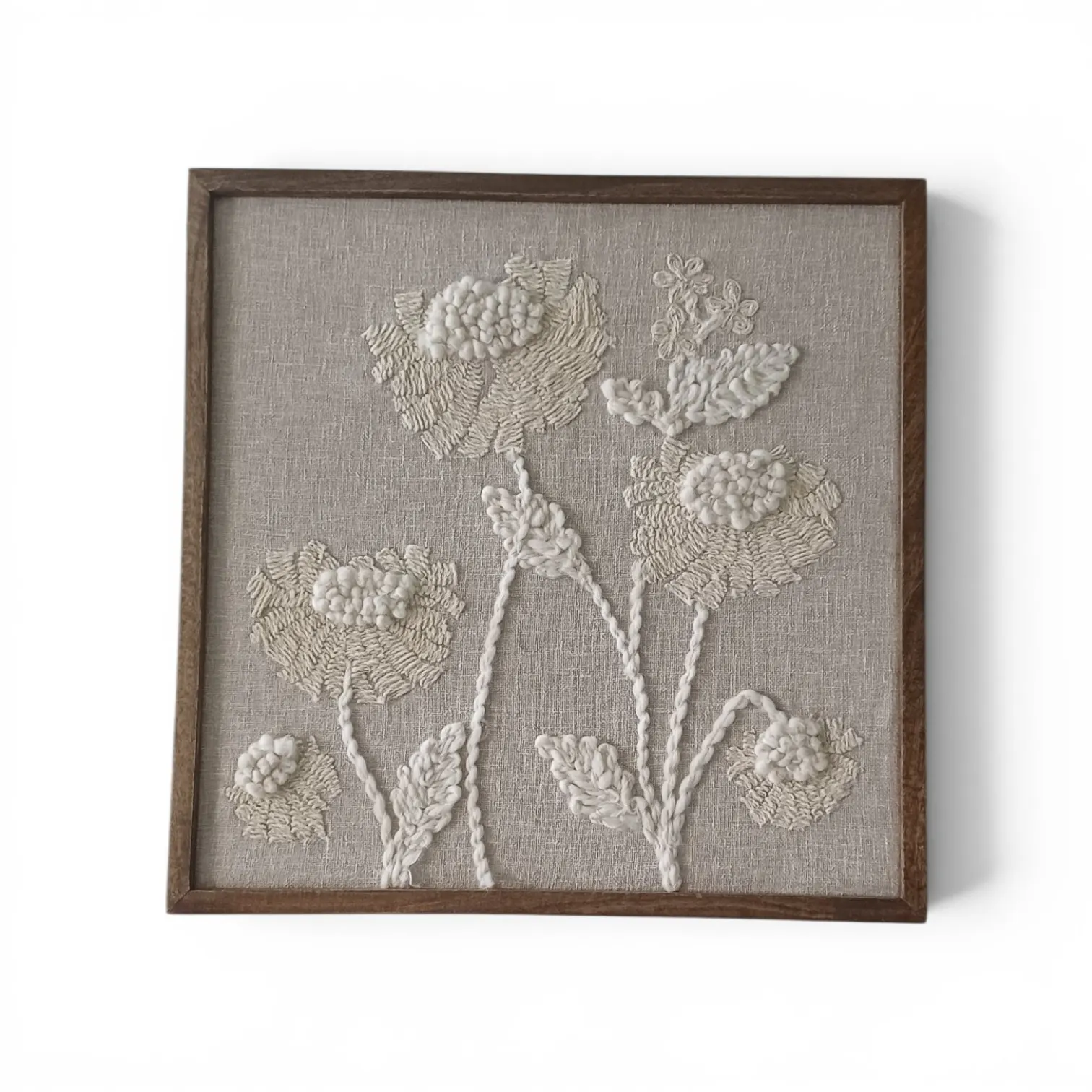 Framed raised embroidery of ivory flowers on a grey linen ground, in a wooden frame
