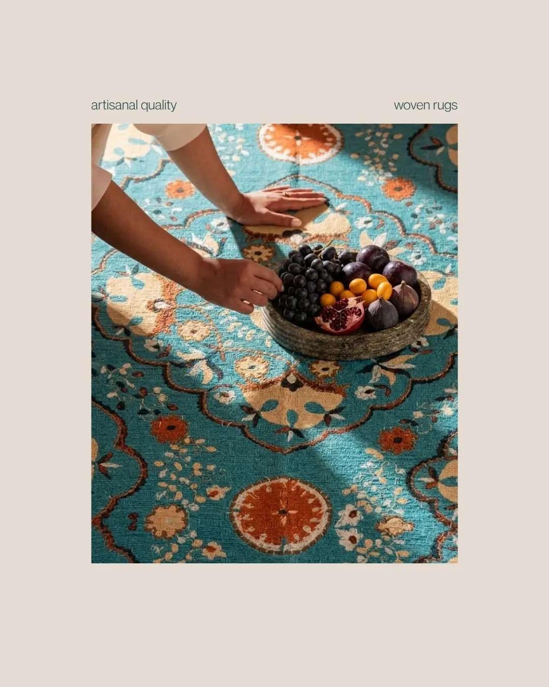 A teal rug with cream, coral and gold flowers, with hands placing a bowl of fruit on it